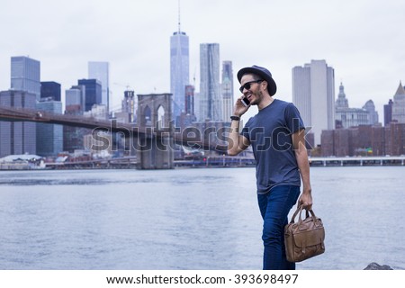 Young entrepreneur making a phone call and carrying a briefcase in New York