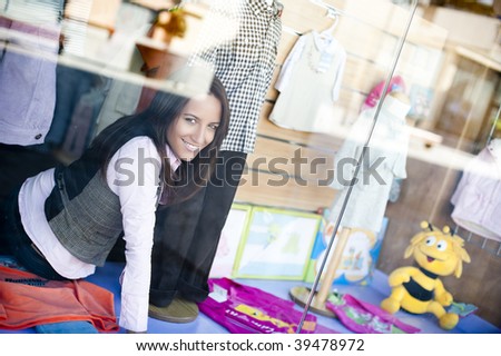 Young beautiful shop assistant working at the shop window