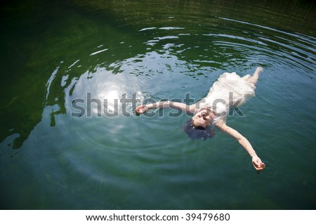 Beautiful young woman on white dress floating in lake, relaxing body and mind.