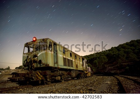 Rusty old train at night with star trails.Star movement is caused by Earth\'s rotation and camera\'s long exposure.