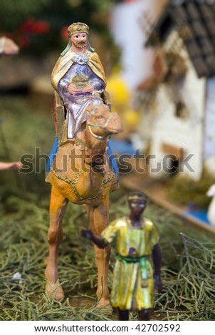 Older wise king with dromedary and page. Focus in wise king figurine.