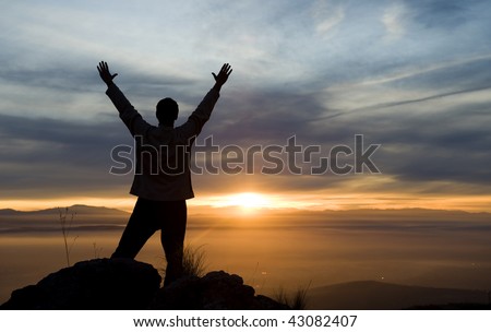 Raised arms man against beautiful sunset.