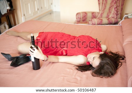 Young woman in party dress drinking wine in her bedroom
