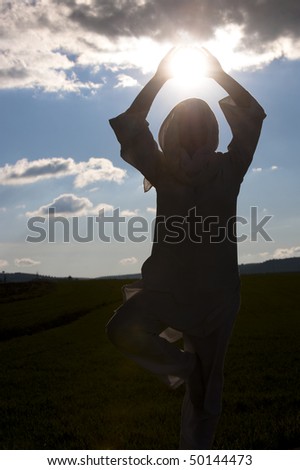Young woman doing meditation with sun in her hands.