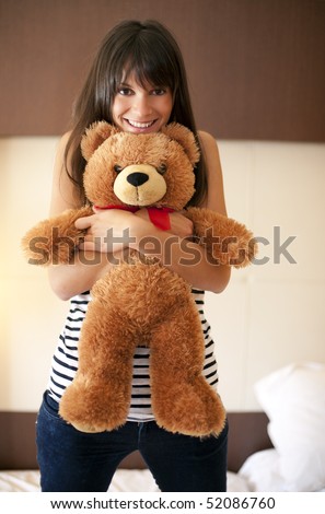 Young woman with teddy bear in bed