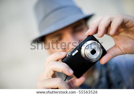 Young man wearing hat taking a picture using a camera