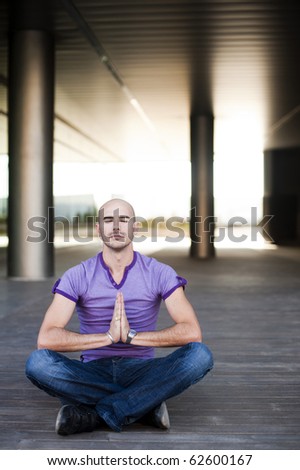 Young attractive man meditating in urban background