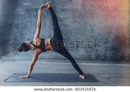 Woman practicing yoga in a urban background (side plank pose, vasisthasana)