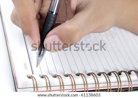 man's hand writing on a book