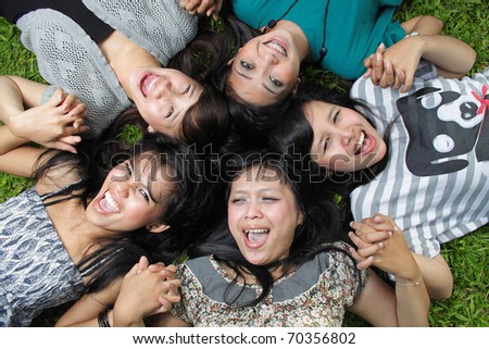 Smiling Happy girl friends group lying down in the park