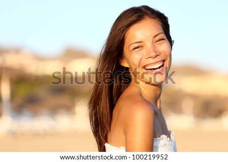 Summer woman portrait. Asian girl smiling happy laughing on beach vacation enjoying warm sunshine. Gorgeous mixed race Asian Chinese / Caucasian female model outside.