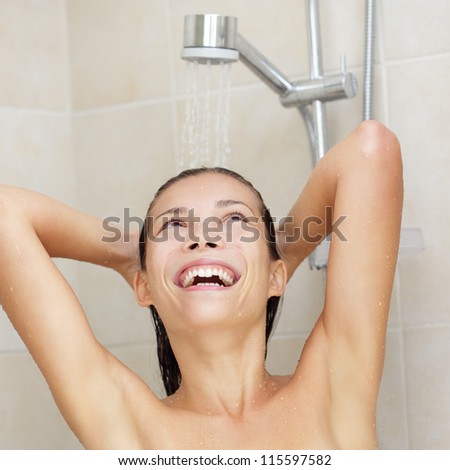 Shower woman smiling happy enjoying water showering and washing hair with joyful and blissful expression. Lifestyle photo of fresh young mixed race Asian Chinese / Caucasian female model in bathroom.