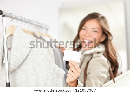 Gift card woman shopping clothes. Happy shopper holding showing gift card or business card in store while shopping for clothing.