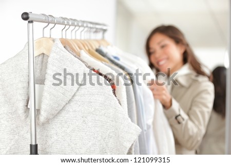 Clothing. Woman shopping clothes in store looking at clothing rack. Focus on winter sweater in foreground.