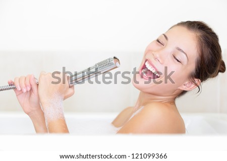 Bath Woman Singing In Bathtub Using Shower Head Having Fun. Funny Photo Of Cute Young Mixed Race Woman.