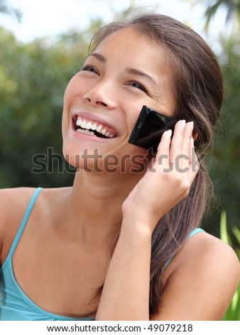 Beautiful smiling asian talking and laughing on the mobile phone.