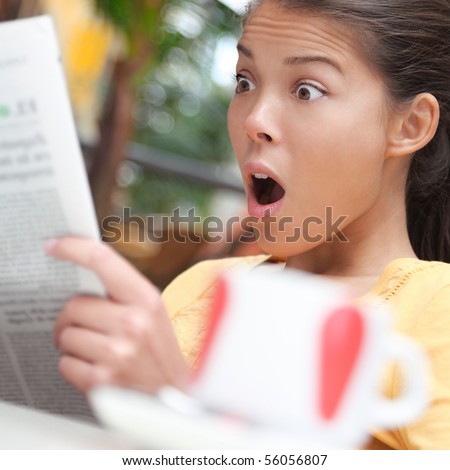 Woman shocked over shocking news in newspaper (gossip, stock market...). Young woman reading the paper on cafe outside.