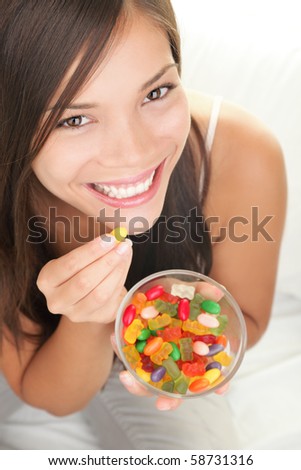 Candy woman. Girl eating winegum gummy bears and other sweets smiling looking at camera.