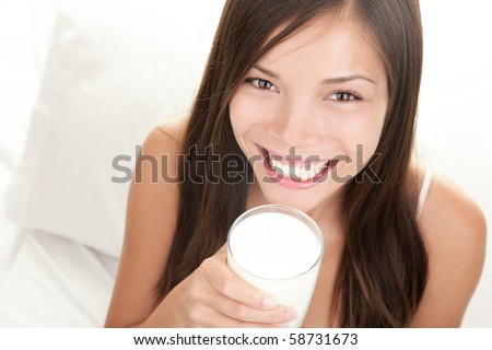 Woman drinking milk. Happy and smiling beautiful young woman enjoying a glass milk.