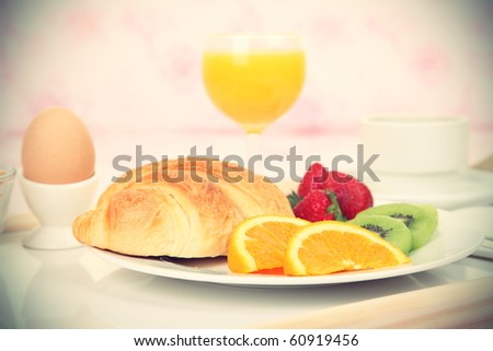 Breakfast tray. Continental breakfast tray on bed with coffee, orange juice, croissant, strawberries and kiwi. Shallow depth of field.
