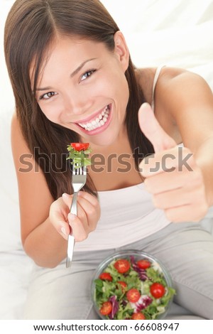 Salad. Eating healthy concept showing happy woman eating salad giving thumbs up.