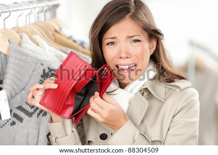 empty wallet - woman with no money in purse shopping. Female shopper in clothes store upset crying as she is out of money. Funny image of mixed race Caucasian / Asian woman.