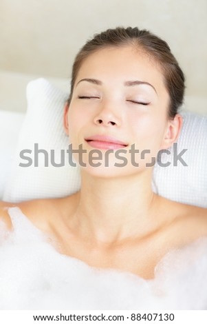 Woman in bath relaxing. Closeup of young asian woman in bathtub bathing with closed eyes.
