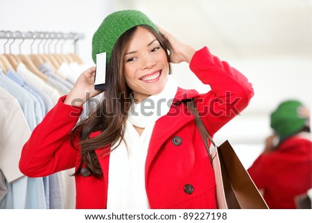 Hat woman. Shopper trying on hat looking in mirror in clothing shop. Beautiful smiling Asian Caucasian female model on shopping trip.