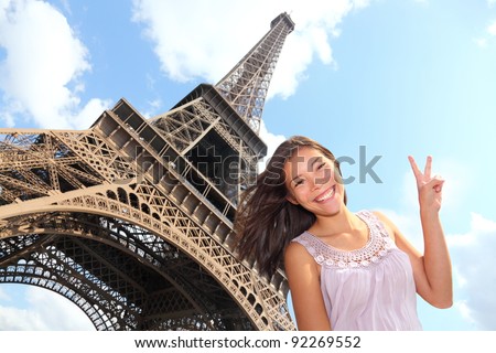 Eiffel Tower tourist posing smiling by Eiffel Tower, Paris, France during Europe travel trip. Young happy excited multiracial Asian Caucasian woman in her 20s.