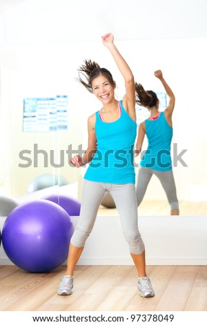 Gym aerobics fitness dance instructor. Woman dancing happy in fitness center. Young beautiful mixed race Caucasian / Chinese Asian female fitness model.