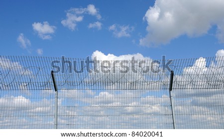 blue sky behind a fence with barbed wire