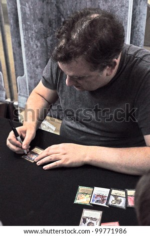 TURIN - APRIL 1: Mark Tedin, artist and author of Magic The Gathering, signs a card during the tournament Grand Prix Turin on April 1, 2012 Turin, Italy.