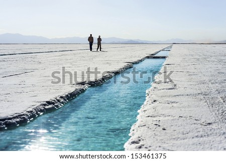 People walking near salt water pool on the Salinas Grandes salt flats in Jujuy province, northern Argentina.