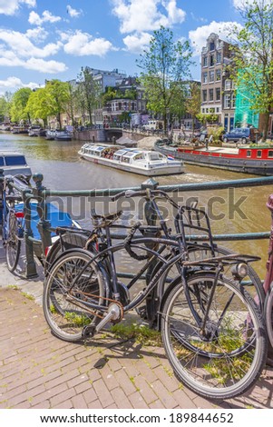 AMSTERDAM, NETHERLANDS - JUNE 15, 2013: Typical bicycles, the most popular transportation system in Netherlands, parked on Amsterdam bank canal