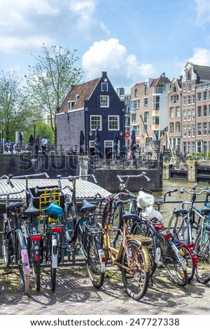 AMSTERDAM, NETHERLANDS - JUNE 15, 2013: Typical bicycles, the most popular transportation system in Netherlands, parked on Amsterdam bank canal