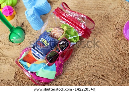 Toddler beach bag and toys on beach sand