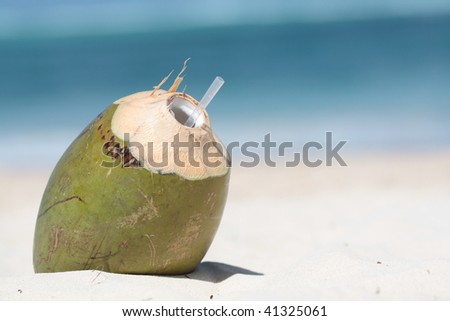 Coconut drink on the sand with sea in background