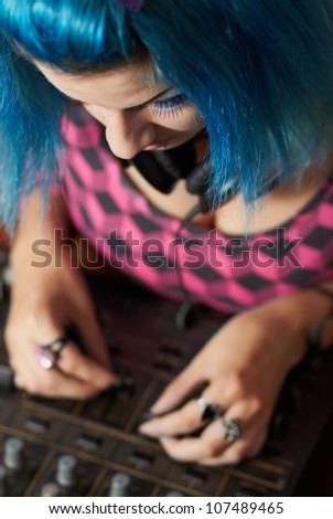 Cute female disc jockey playing music on a professional sound equipment - 4-channel club mixer