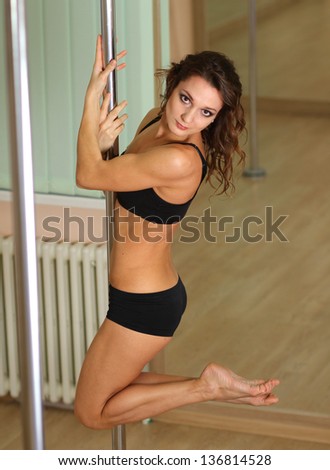 Young professional pole dancer exercising in the studio in strip plastic dance