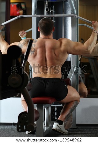 Big pumped powerlifter with a tattoo on his arm exercising in gym
