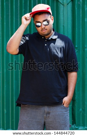 Cool young black man posing at the green garage wall on his block