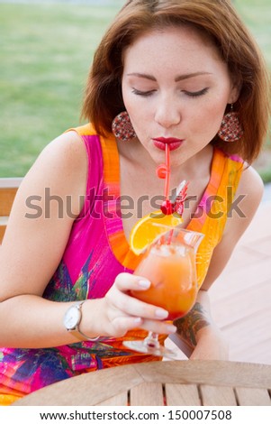 Beautiful young lady enjoying her fresh cocktail sitting in a restaurant outdoors