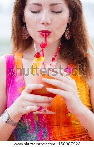 Beautiful young lady enjoying her fresh cocktail sitting in a restaurant outdoors