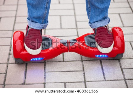 Feet of a woman riding on modern red electric mini segway or hover board scooter. New transportation technology is so fun and easy to ride,produces no air pollution to the atmosphere.