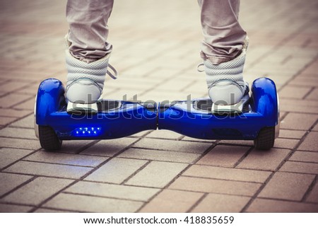 Person riding a modern blue electric mini segway or hover board scooterin outdoors. Popular new city transport that is easy and fun to ride and makes no air pollution to the atmosphere