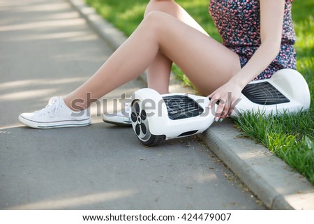 Female with electric mini hover board scooter in green park. Eco city transportation on battery power, produce no air pollution to atmosphere