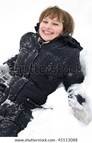Smiling chick laying in snow wrapped in warm coat