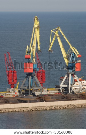 Two heavy industrial cranes working at the commercial dock in the middle of a day
