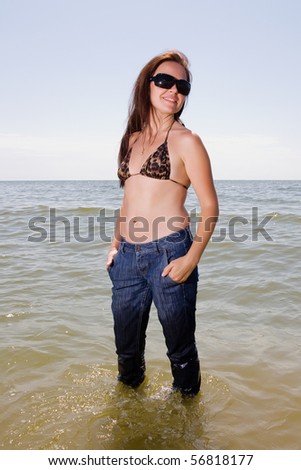 Girl stands in wet jeans in the water of a sea
