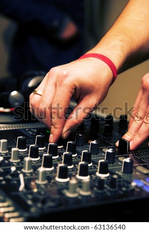 DJ playing music on professional mixing controller in the nightclub